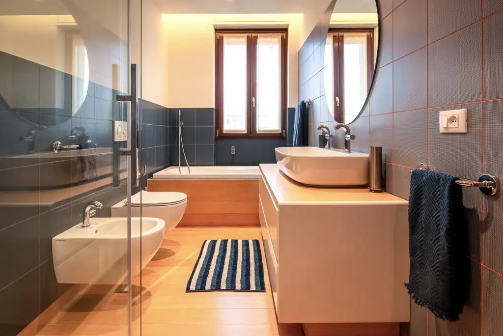 Bagno con pavimento in parquet e vasca sotto la finestra